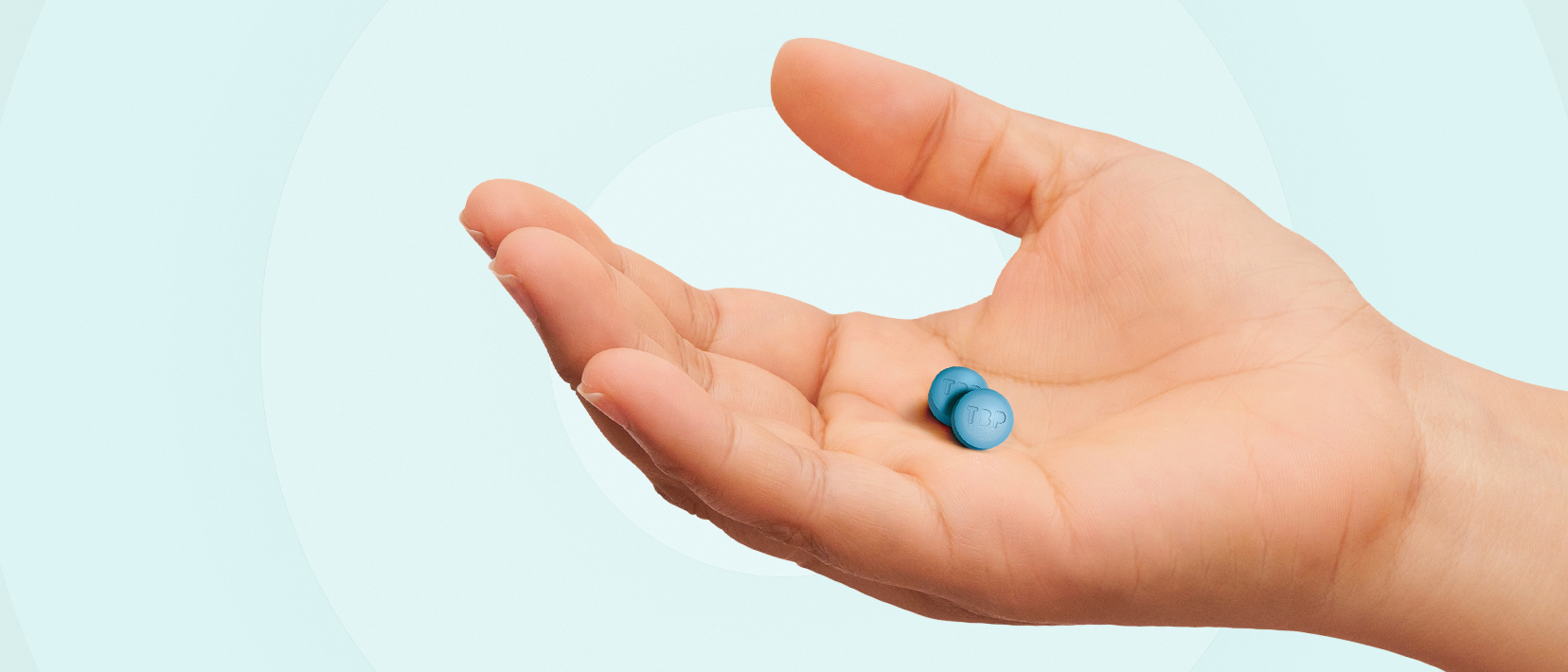 A hand holding two blue UTEBZI tablets. A hand holding two blue UTEBZI tablets.